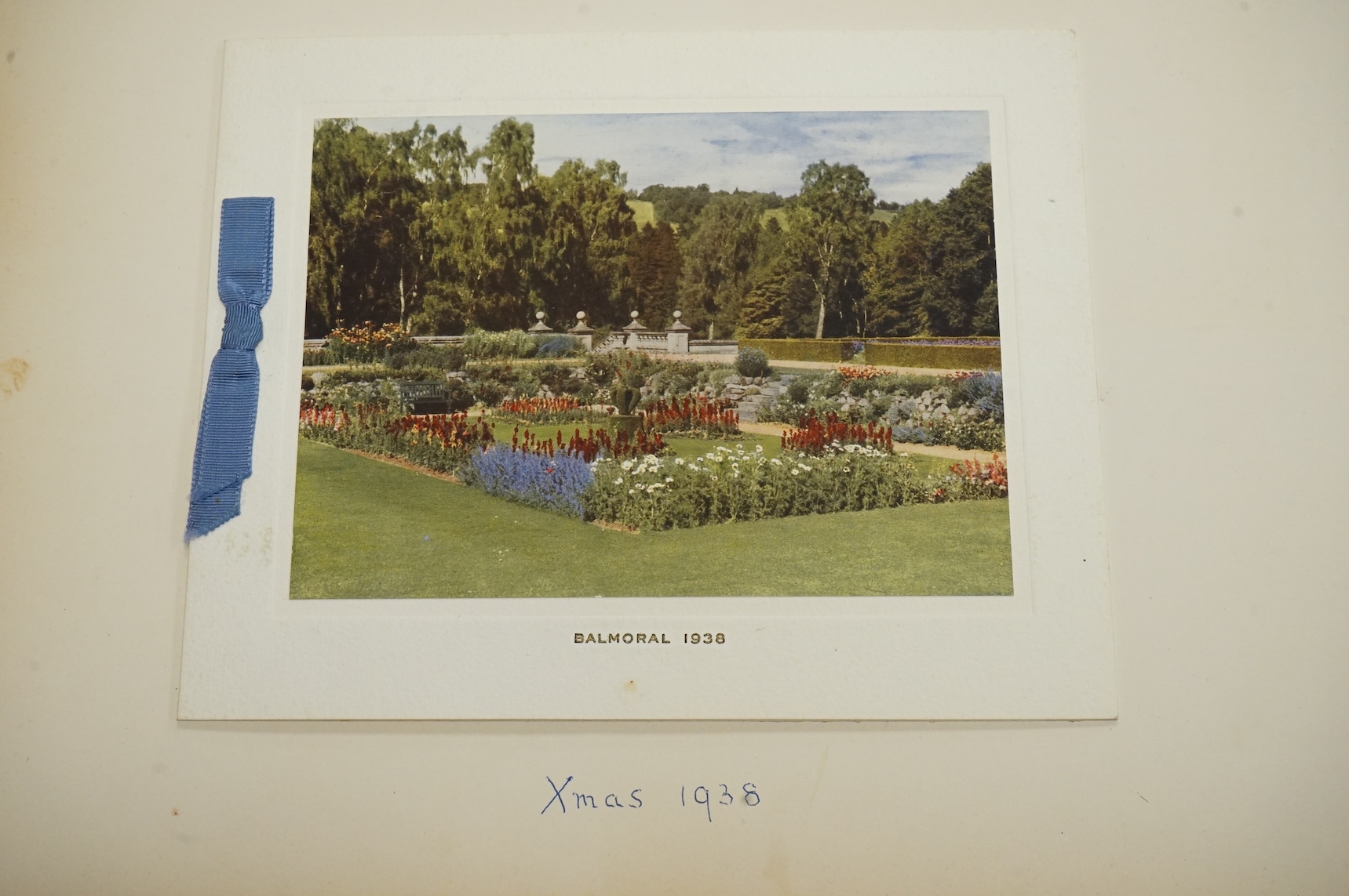 HRH King George VI and Queen Elizabeth signed Christmas card for 1938, with a colour photograph of the garden at Balmoral Castle entitled ‘Balmoral 1938’ to the cover, pasted onto a card leaf from a photograph/scrap albu